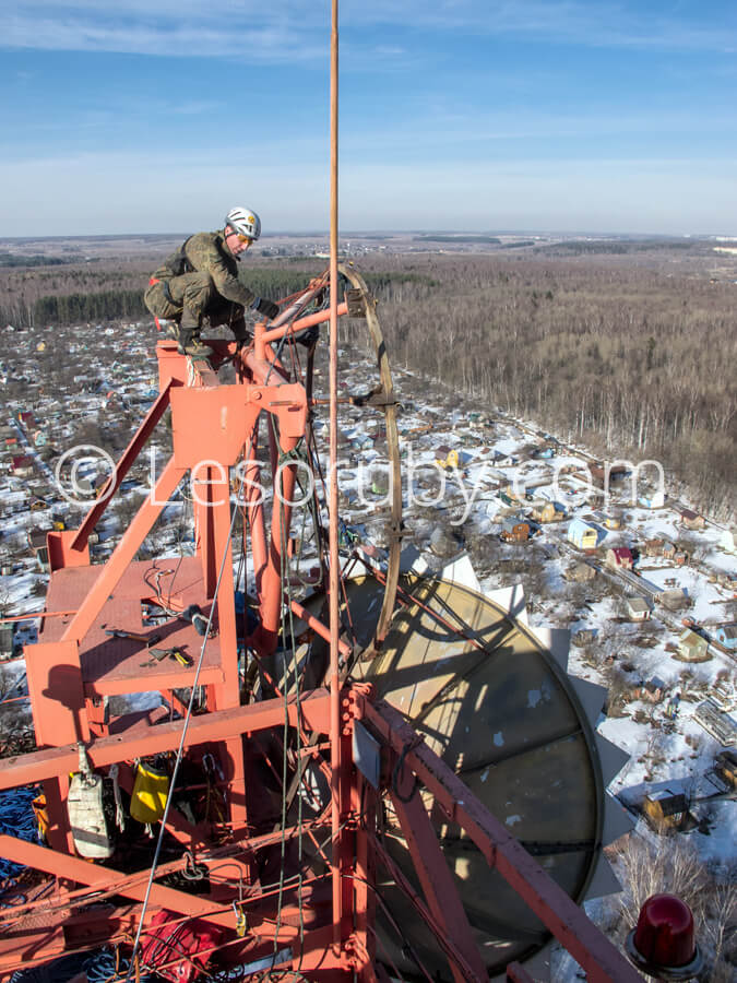 Промышленный альпинист демонтирует радиорелейную антенну с верхней площадки мачты